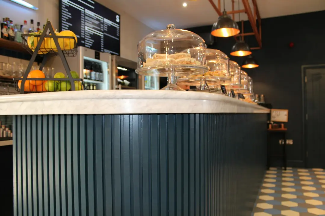 A marble café counter with cake domes under pendant lights