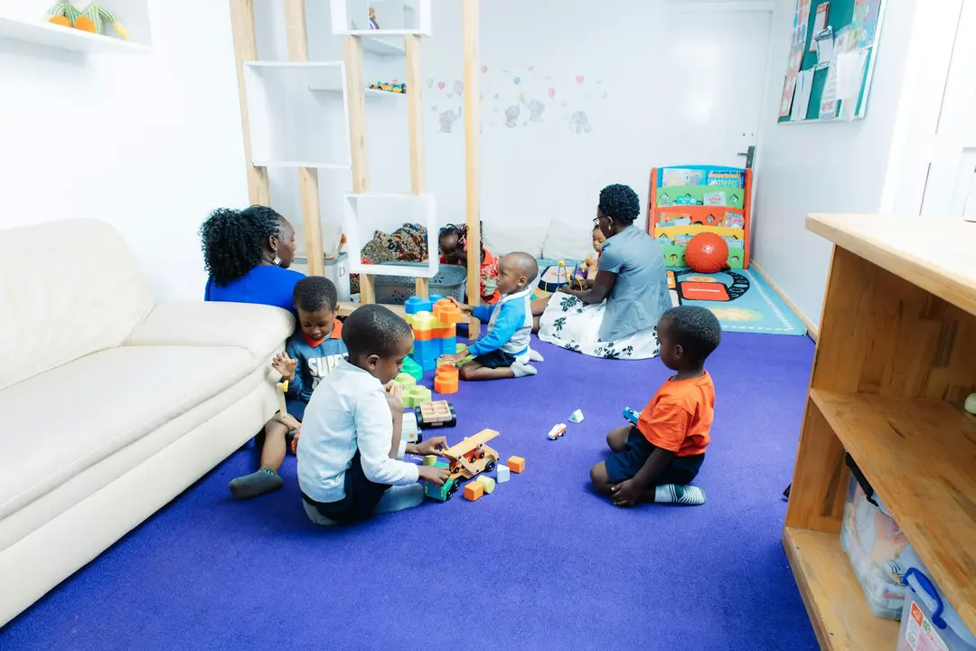Young children playing with toys on a blue carpet in a playroom