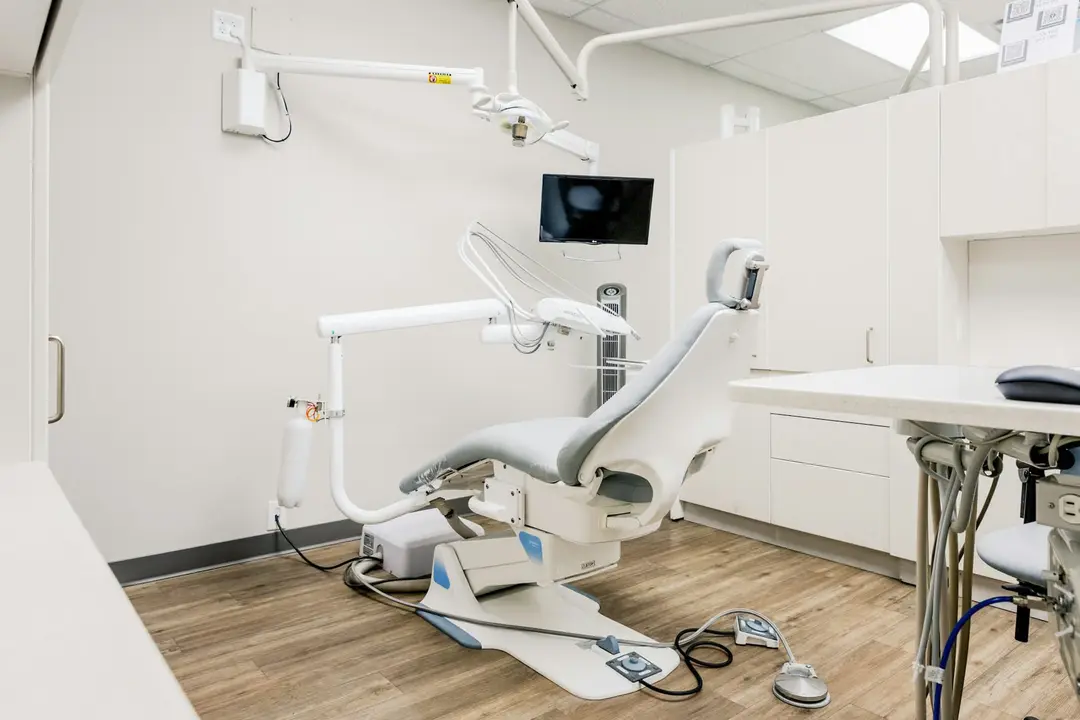 A dental treatment room with a white chair and wooden floor