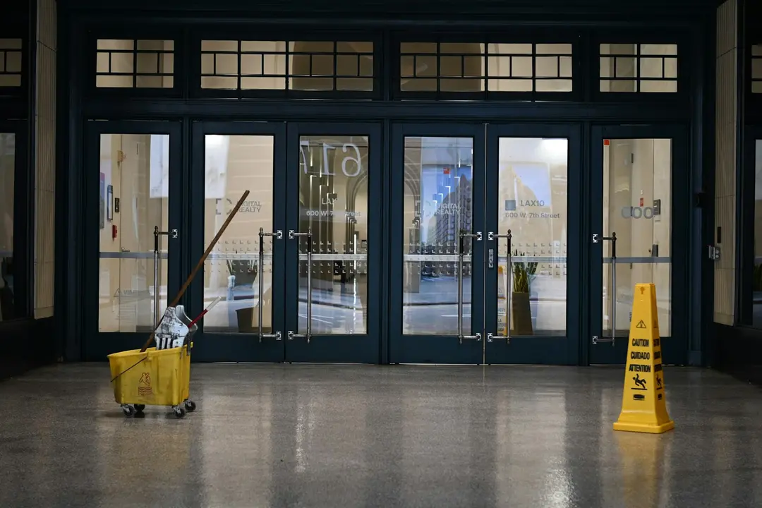 A mop bucket and a wet floor sign in an office building lobby