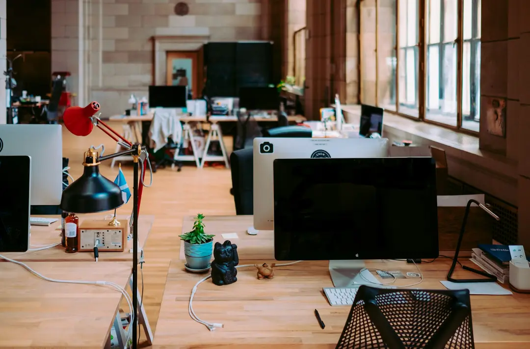 Desks and monitors in the same warm open-plan office