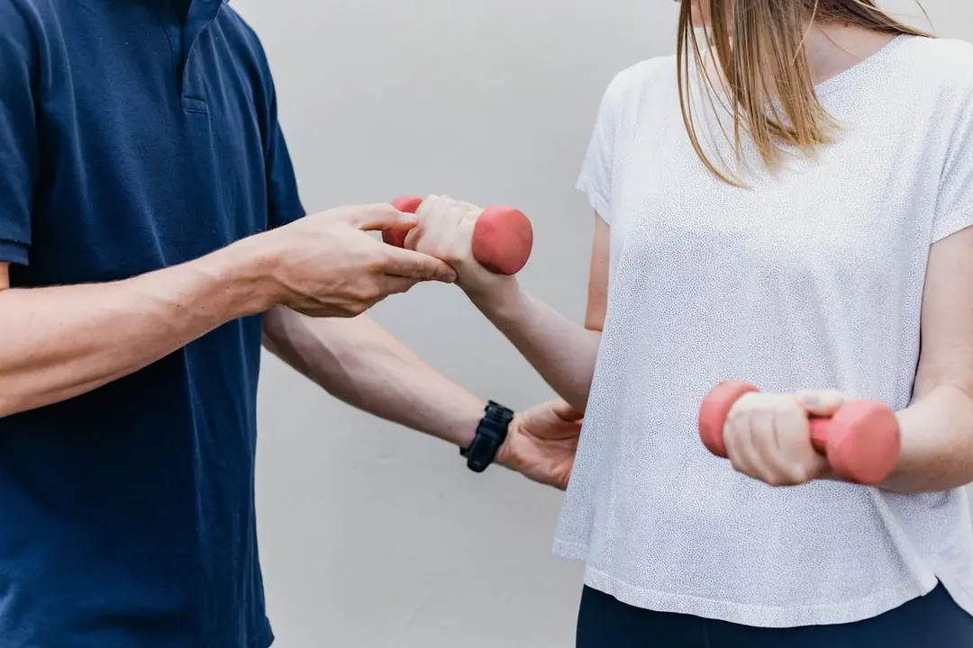 A physiotherapist guiding a patient through a dumbbell exercise