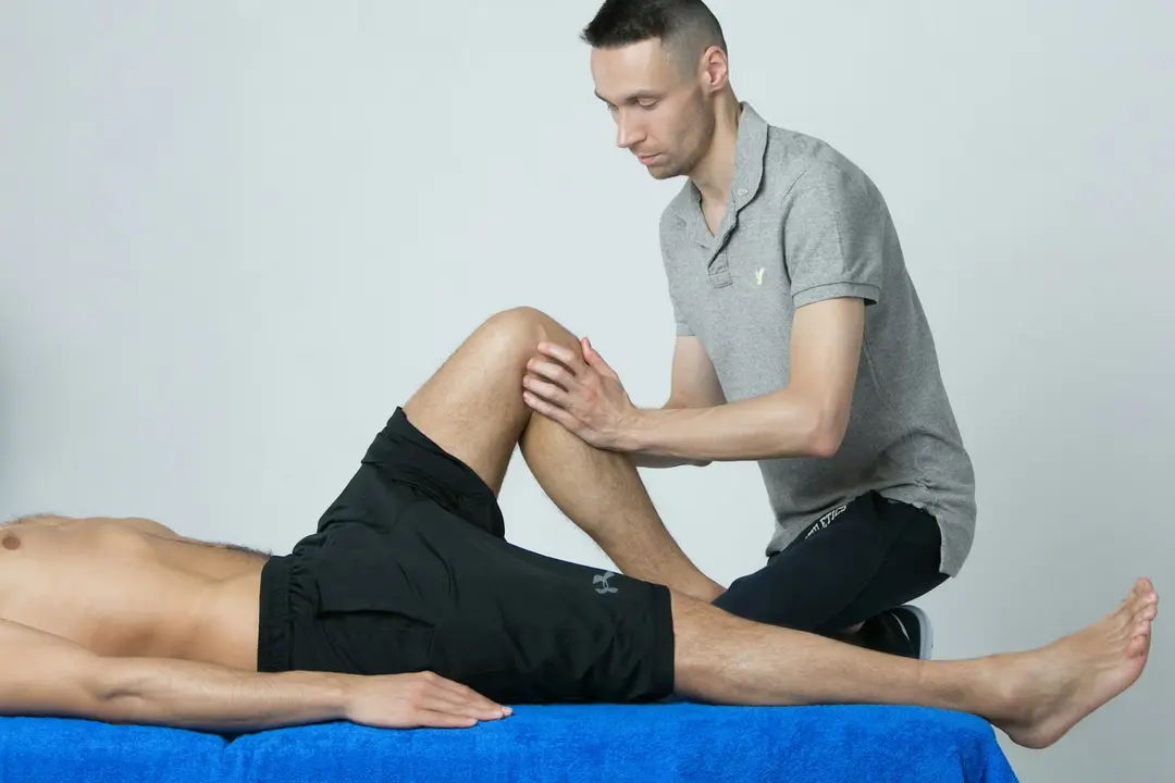 A physiotherapist assessing a patient’s knee on a treatment table