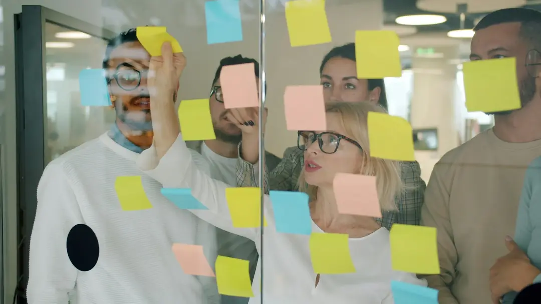 A team arranging sticky notes on a glass wall during a planning session