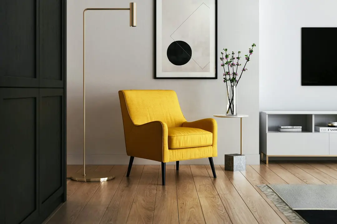 A yellow armchair beside a brass floor lamp and a framed print in a bright living room